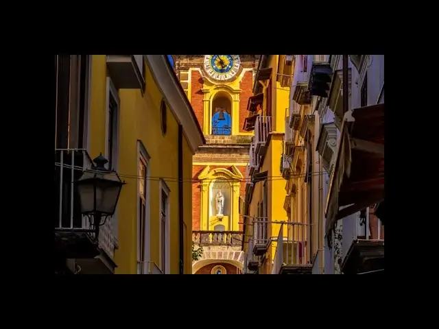 Rue colorée de Naples avec une statue religieuse et une horloge en mai