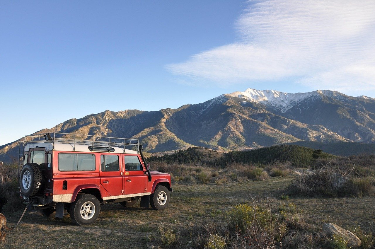 top 11 des meilleurs road trips au monde une jeep sur une falaise avec vu de la montagne